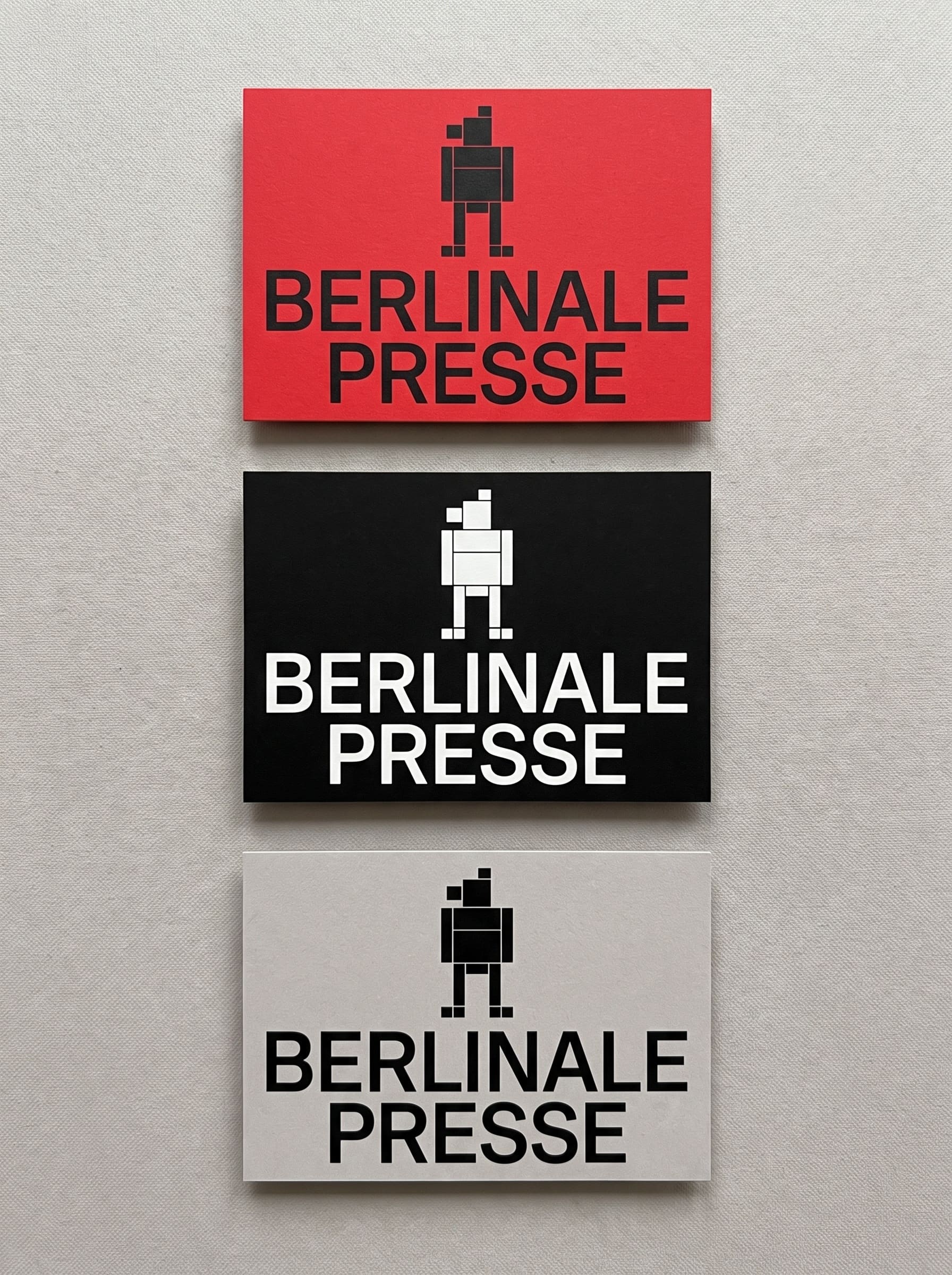 A vertical column of complete red, black, and grey printed accreditation cards, each fully visible with clear margin, showing the identical modular block bear built from flush rectangles on a square grid.