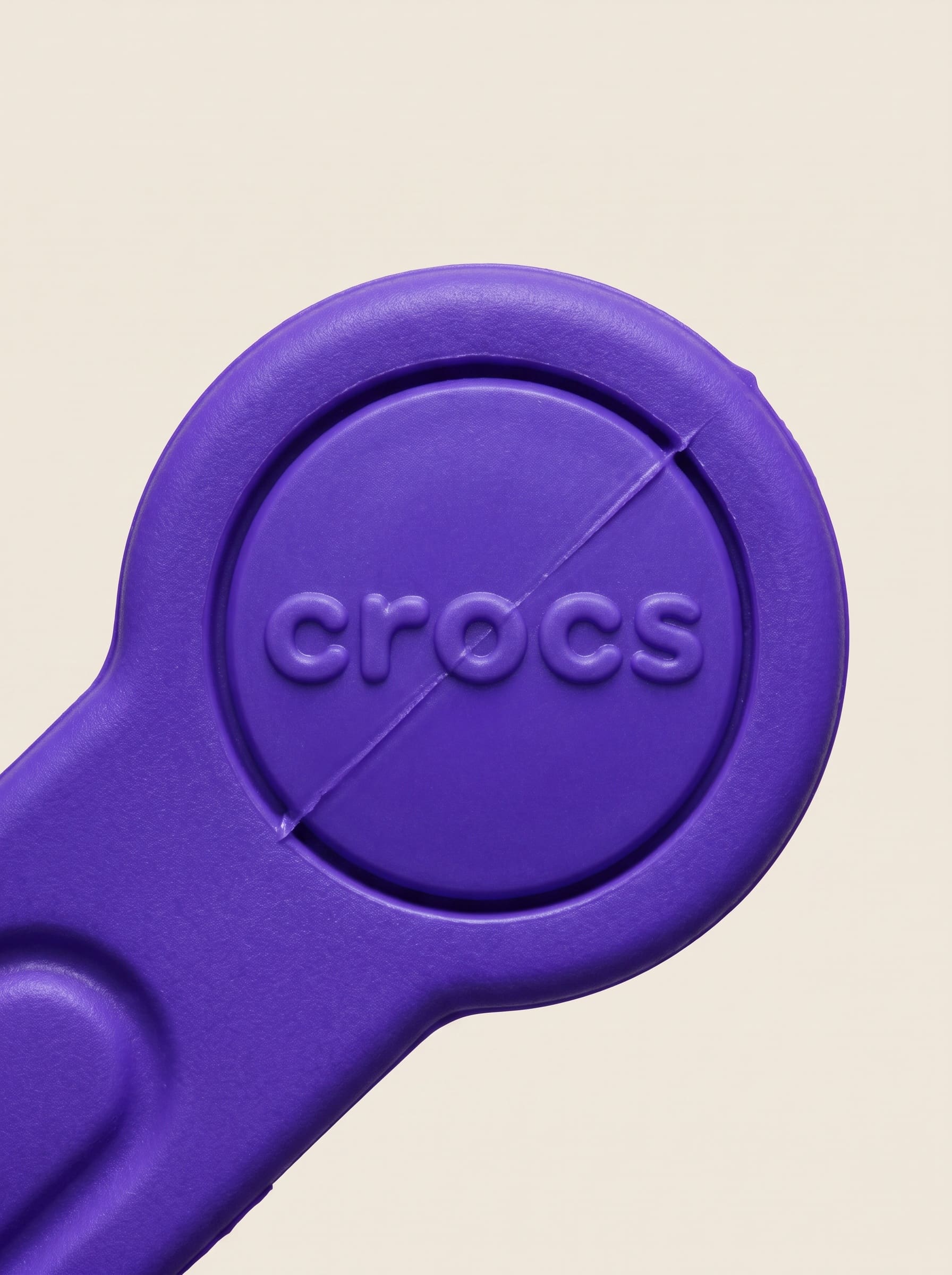Macro of an ultraviolet moulded strap fitting with the CROCS wordmark raised in the resin.