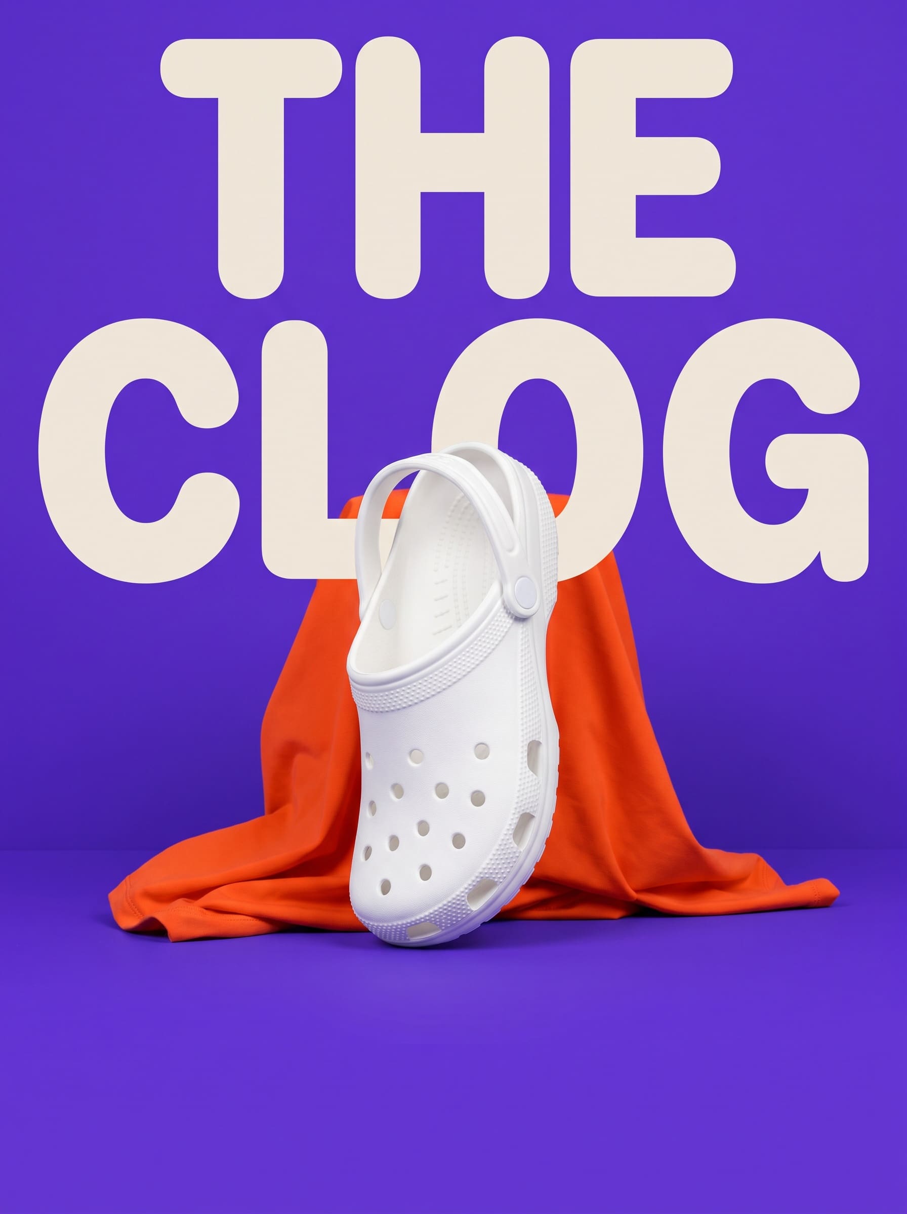 Campaign image with THE CLOG in huge cream type behind a single white clog on a plinth beside a folded orange garment, on ultraviolet.