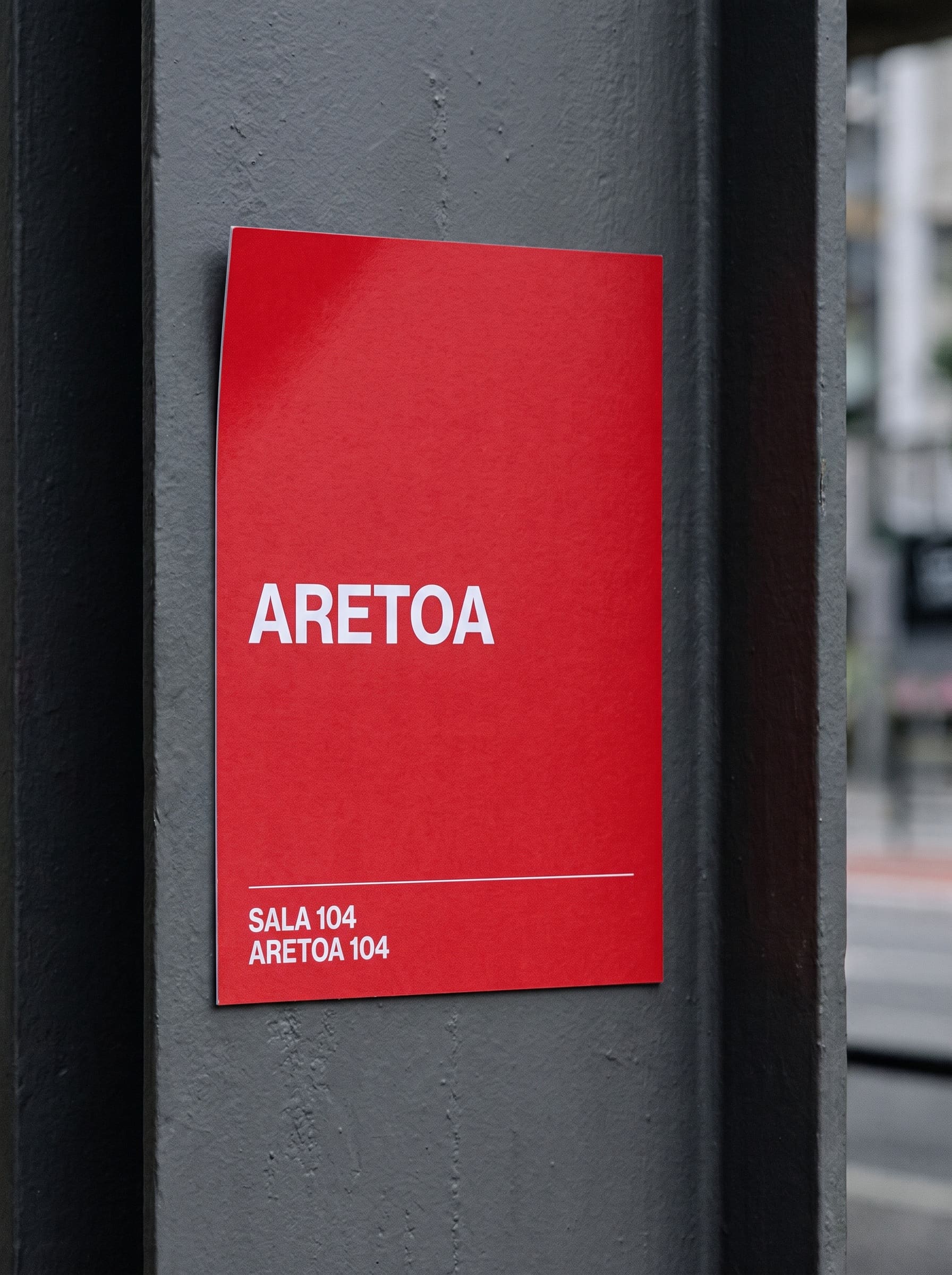 Red uncoated card sign on a grey steel column with GUGGENHEIM and two small caption lines