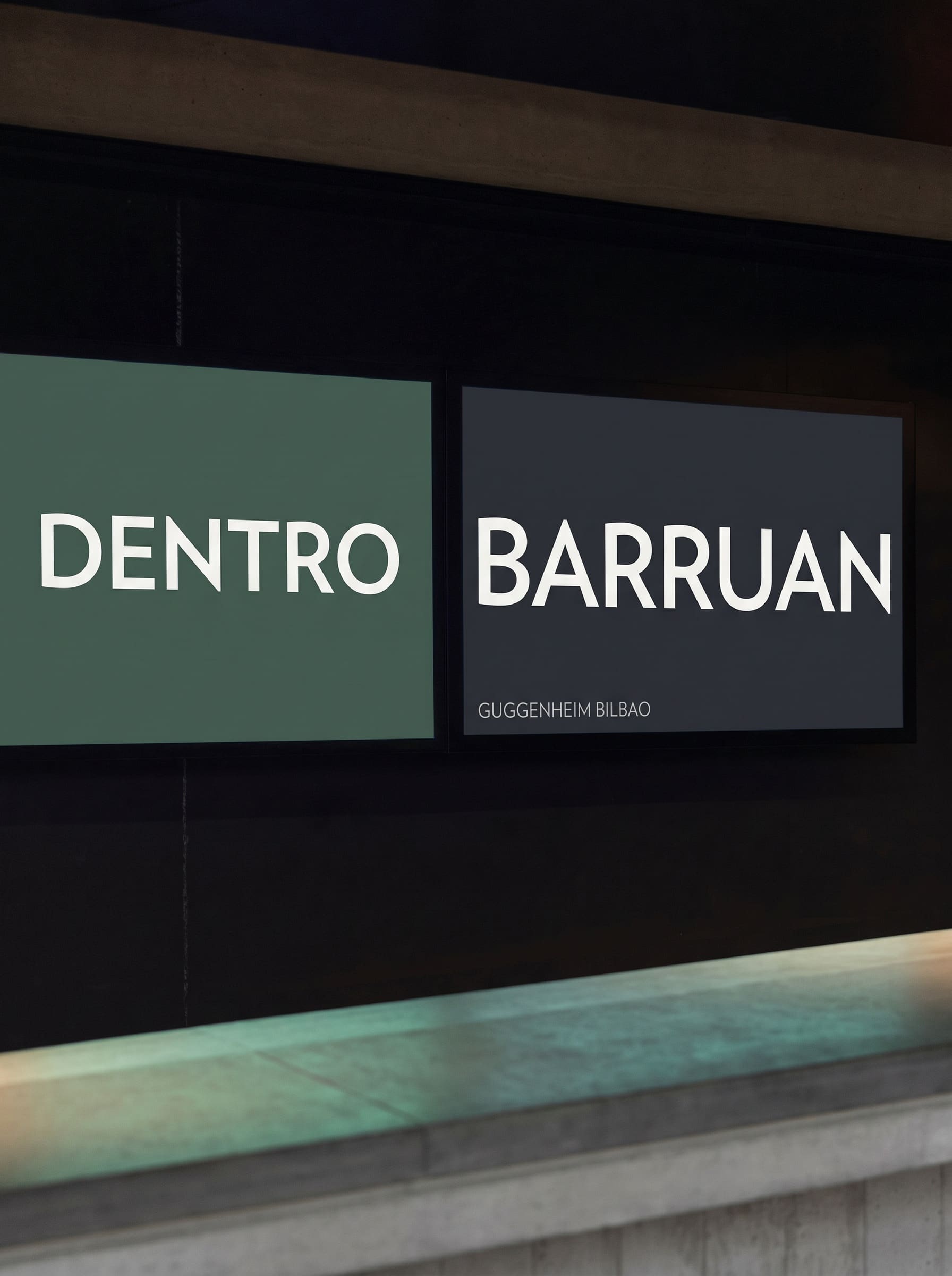 Two lit panels in a dark hall reading DENTRO in cream on green and BARRUAN in cream on slate, with GUGGENHEIM BILBAO beneath