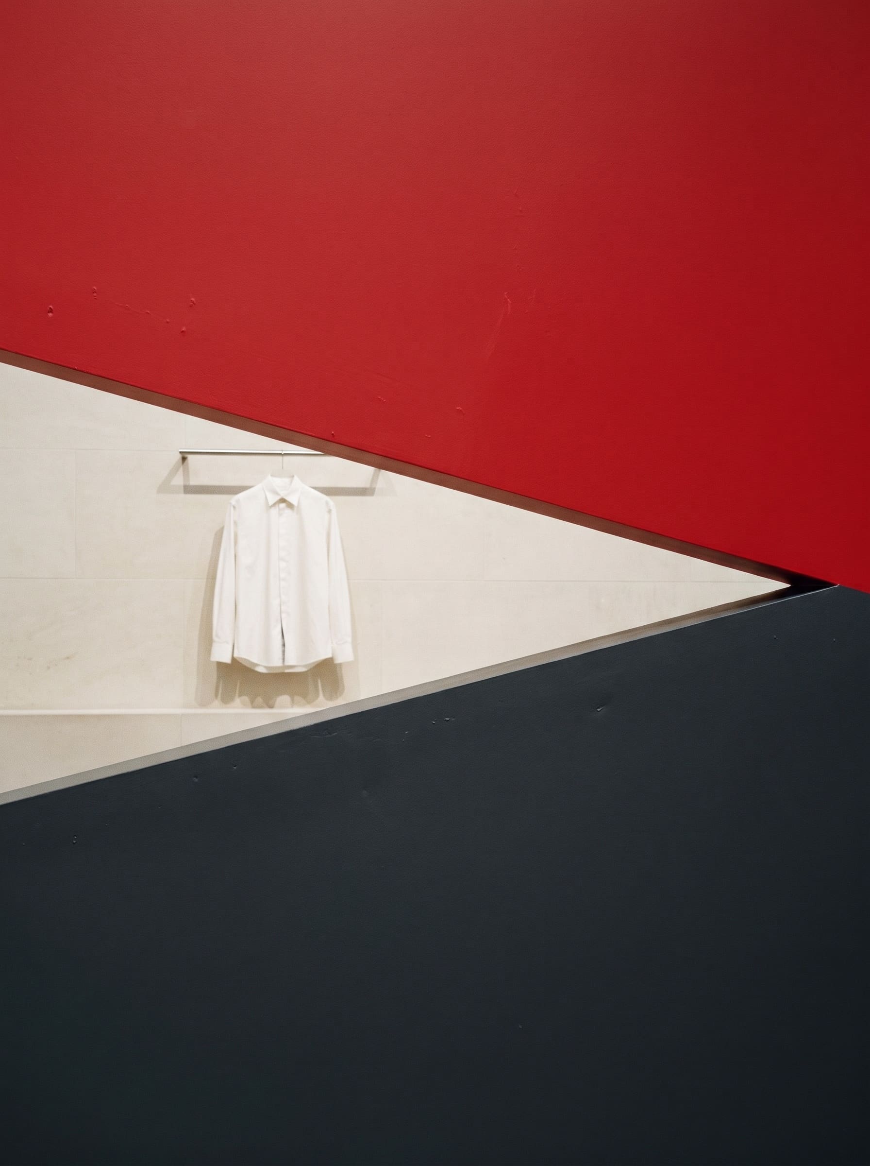 Red and slate planes forming a diagonal wedge with a hung white shirt visible in the gap