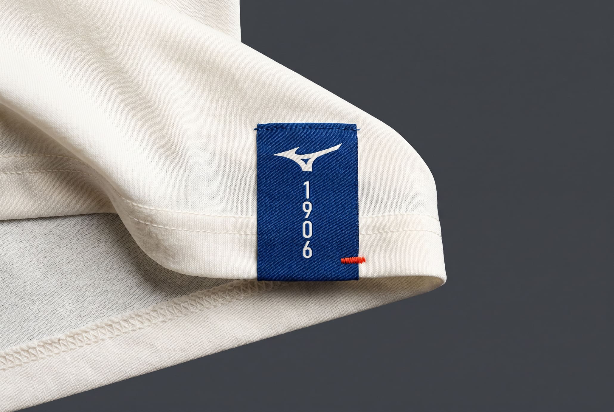 Macro of a woven blue Mizuno label on a bone singlet hem.