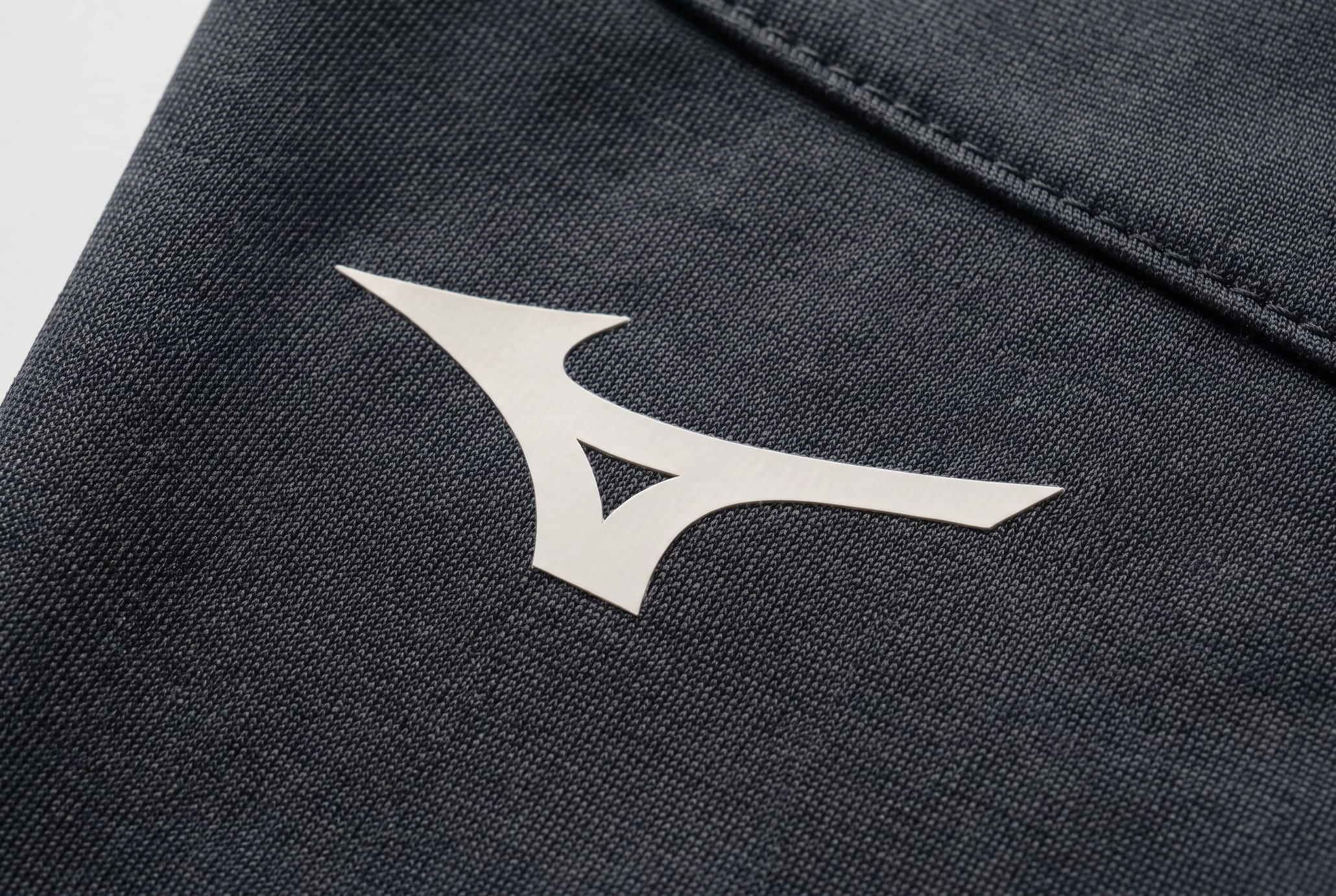 Extreme macro of a white single-stroke Runbird on graphite technical fabric.