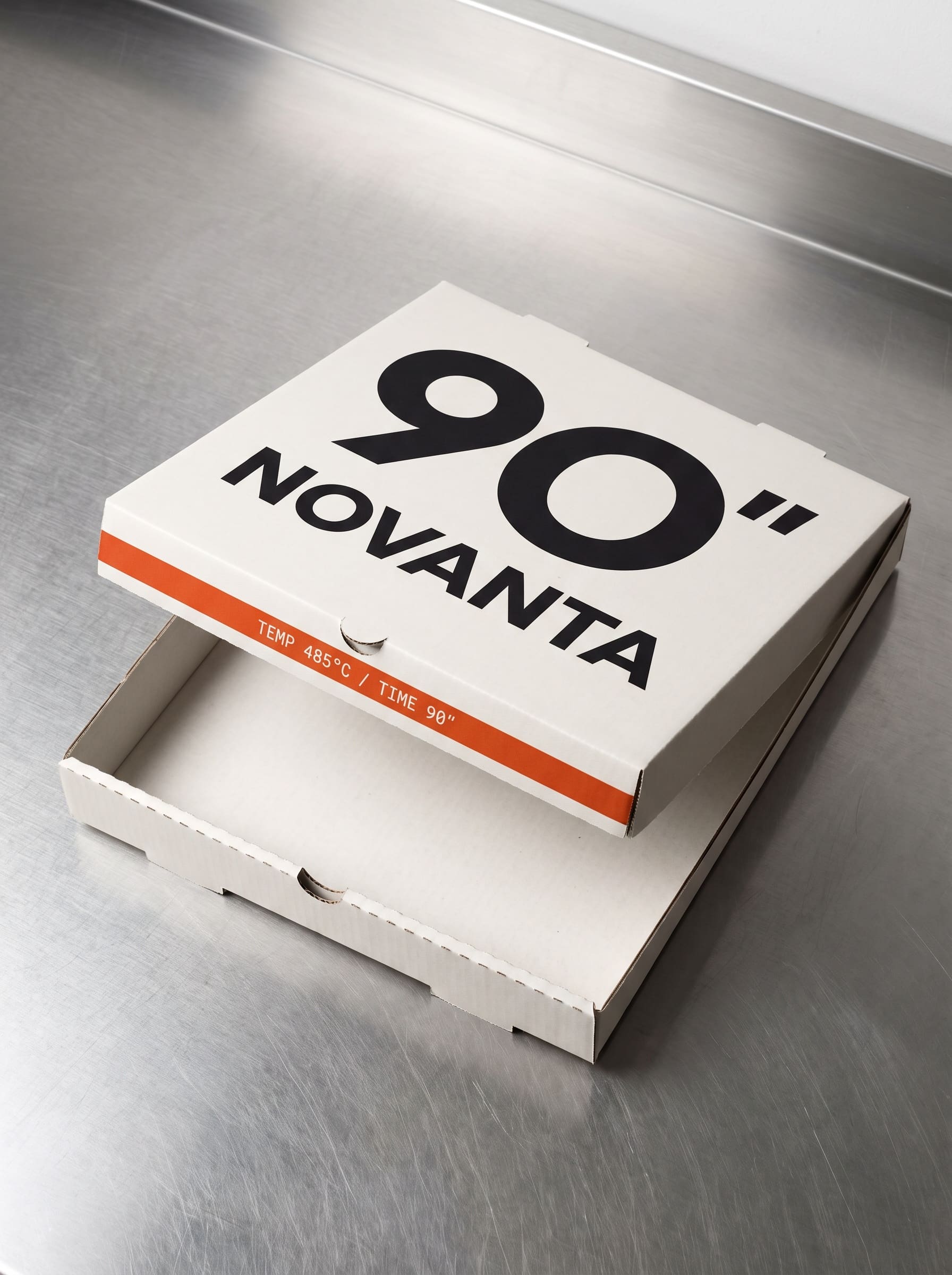 An open white pizza box on a steel counter, the temperature band printed inside the lid