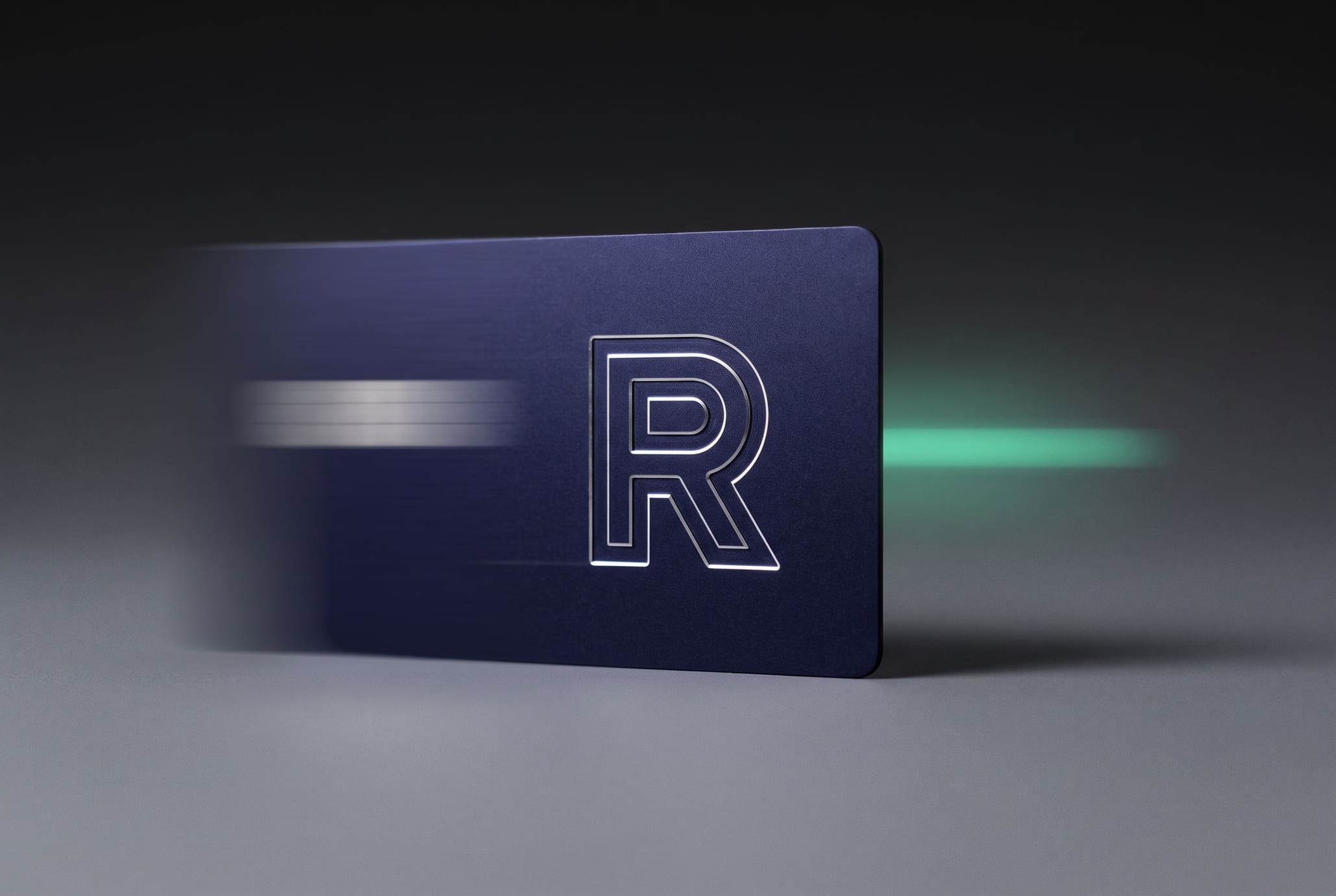 An anodised indigo aluminium payment card spinning flat, its corners blurring into a circular envelope of motion against a graphite gradient, a mint streak trailing behind