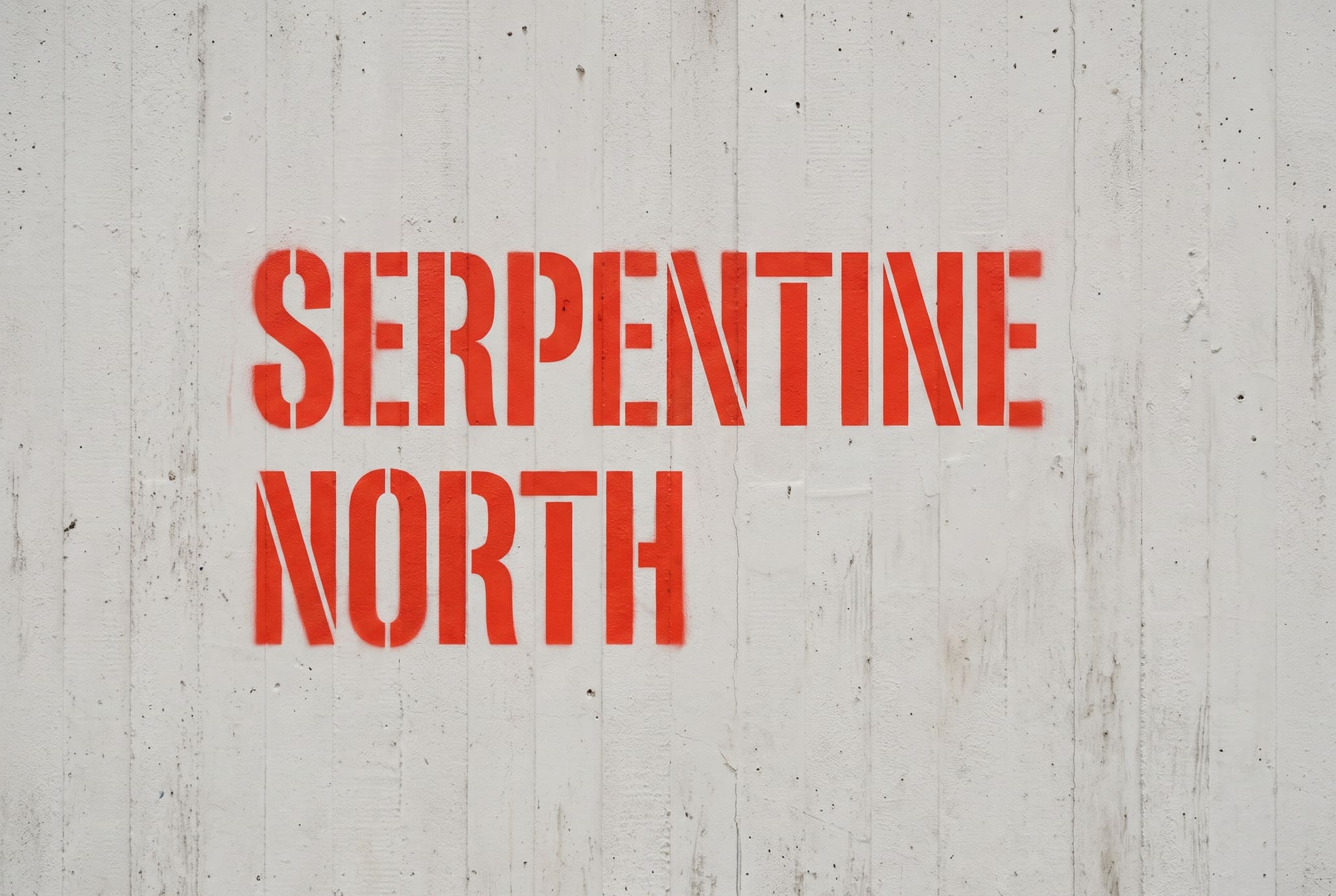 SERPENTINE NORTH stencilled in red paint on a raw concrete wall