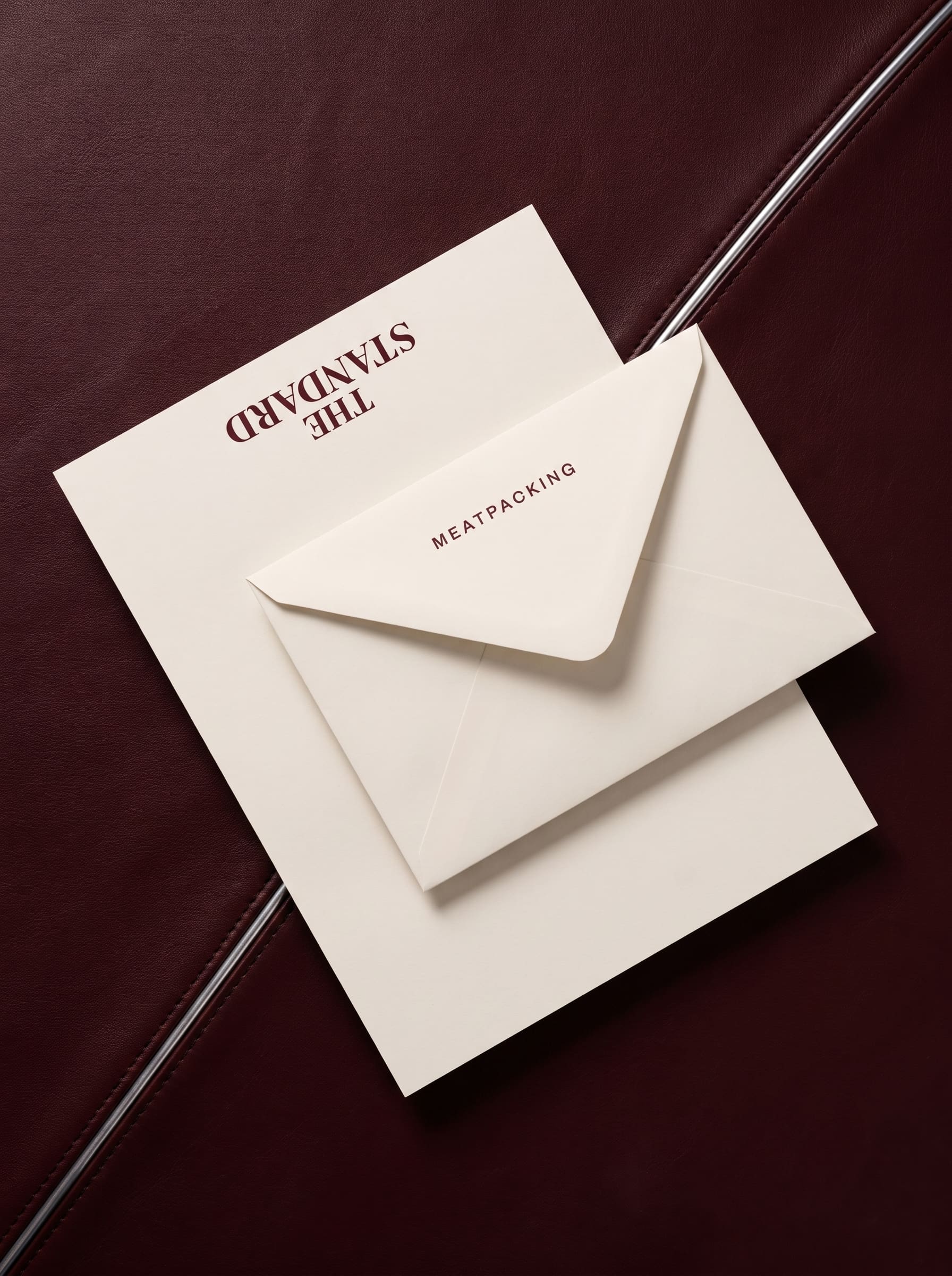 Cream letterhead and envelope photographed from above on oxblood leather, headed with an upside-down wordmark.